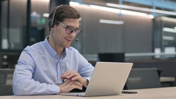 Young Man with Headset Making Video Call on Laptop