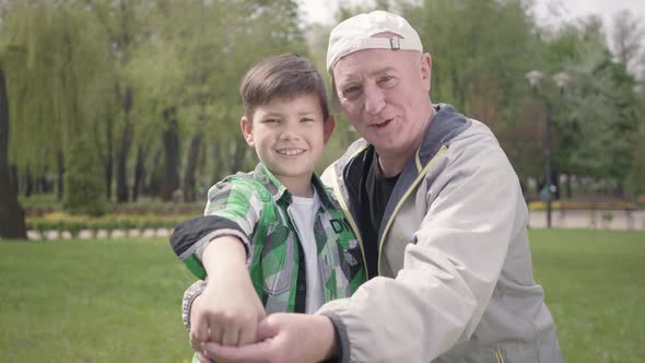 Portrait of Cute Happy Little Boy in a Checkered Shirt and Positive Old Man Looking in the Camera