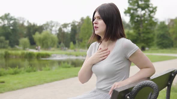 A Young Caucasian Woman is Sick Coughs and Has Respiration Trouble As She Sits on a Bench