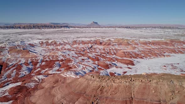 Aerial view of eroded cracks in the red desert of Utah with snow