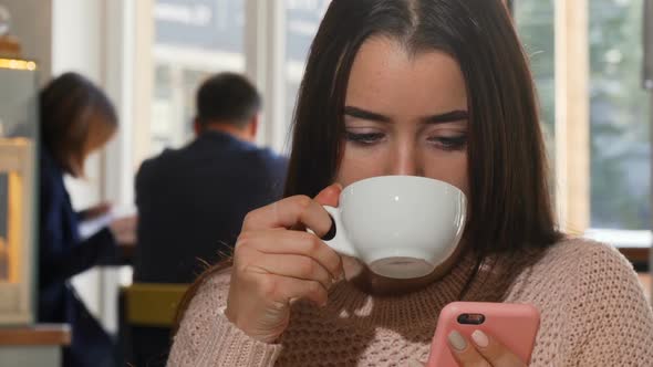 Attractive Woman Drinking Coffee, Using Her Smart Phone at the Cafe