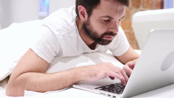 Beard Man Working on Laptop Lying in Bed for Rest