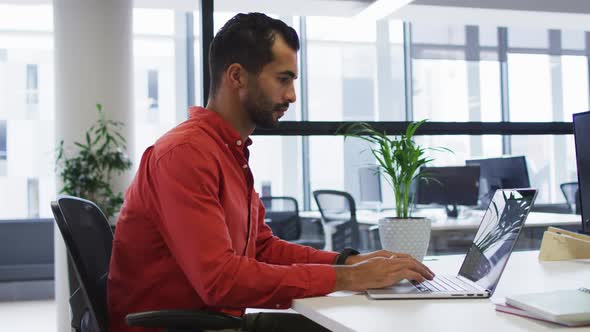 Mixed race businessman sitting at desk using laptop