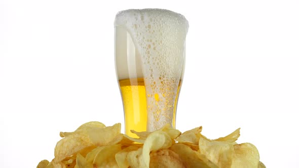 Beer and chips. Pouring beer in glass, potatoes chips around