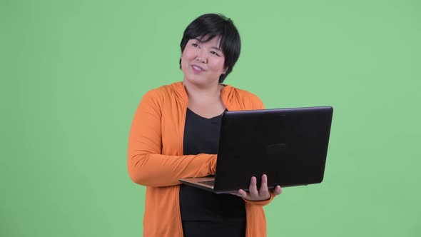 Happy Young Overweight Asian Woman Thinking While Using Laptop Ready for Gym