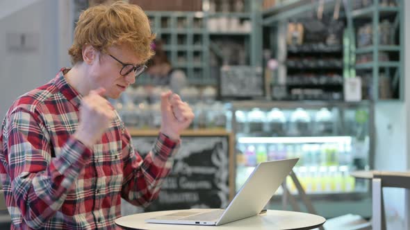 Angry Redhead Man Reacting To Loss on Laptop in Cafe 