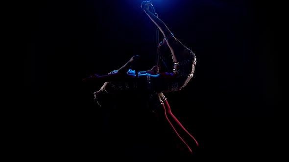 Acrobats Performs a Gymnastic Trick on the Aerial Hoop. Black Background. Slow Motion