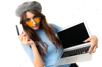 Cheerful woman with long hair holds a money card and laptop isolated on white background