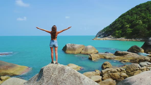 Exotic Beach Girl Stand on Rocky Chunk Drone View