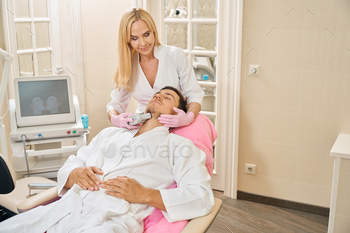 client in the chin area, a man sits in a cosmetology chair