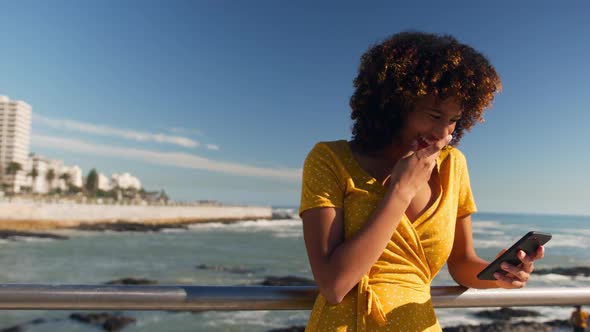 Woman smiling and using phone at beach