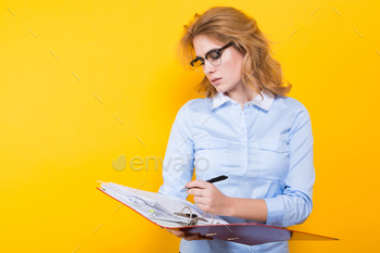 ue shirt and glasses isolated on orange background checking readings in open big folder with files graduate or course work report presentation concept.