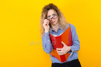 riped shirt and eyeglasses isolated on orange background holding big folder with files graduate or course work report presentation concept.