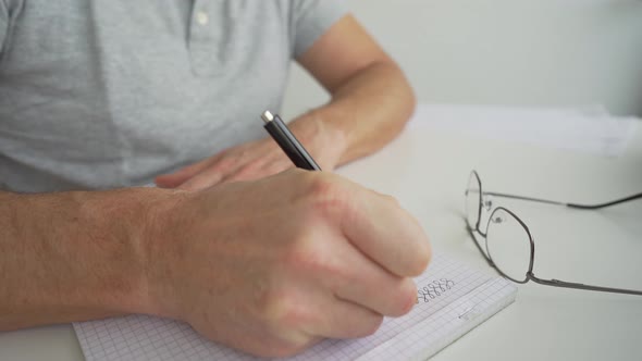 man drawing on a desk to his notepad
