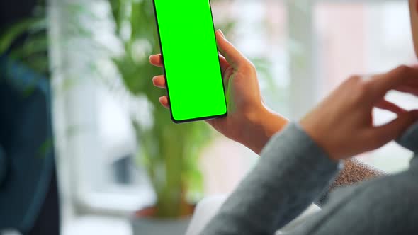 Woman at Home Using Smartphone with Green Mockup Screen in Vertical Mode