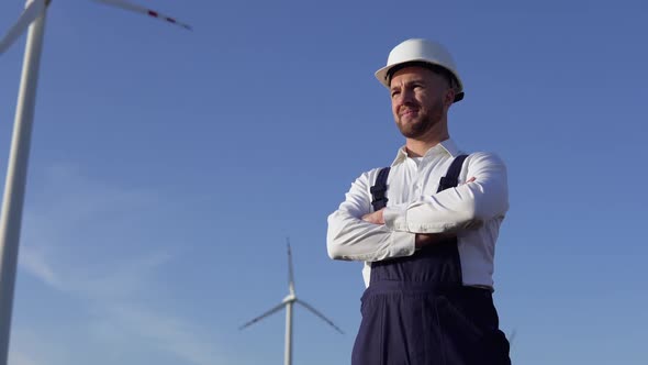 The Power Plant Engineer is Standing in a White Classic Shirt Blue Overalls and a White Helmet on a