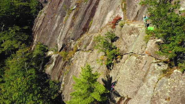 Aerial footage Tilt up on a pair of climbers on a cliff in Maine