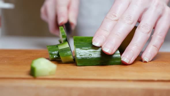 Cutting Fresh Green Cucumber on a Wooden Board in the Kitchen