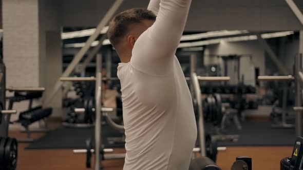 Powerful Man Doing Exercises on the Muscles on the Pull of the Upper Block