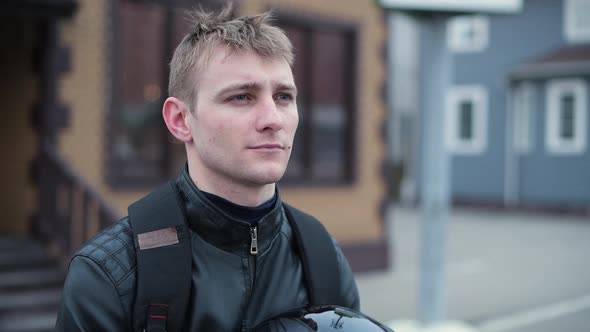 The biker looks in front of himself in the evening, then puts on his helmet