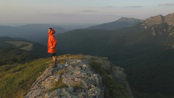 Traveler Man Sitting Alone at Rocky Cliff Looking at the Beautiful Sunset