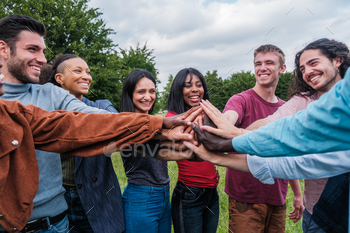 Group of young people joining hands to join forces and work as a team