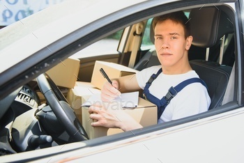 Young Delivery Man Checking List On Clipboard In car