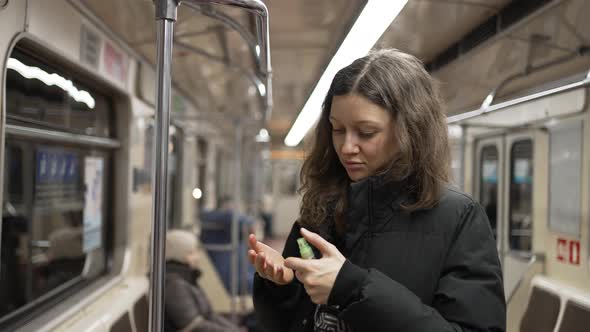 Young Woman Uses Sanitizer After Holding Handrail in Subway