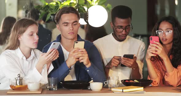 Crop View of Millennial Friends Phubbing Smartphones While Spending Time Together in Cafe. Group of