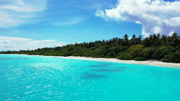 Aerial flying over scenery of idyllic seashore beach lifestyle by blue sea and white sand background