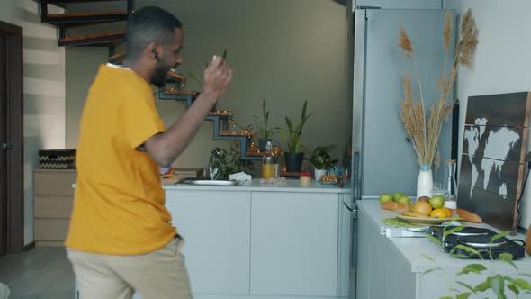 Carefree African American Student Dancing and Singing in Kitchen Having Fun Alone