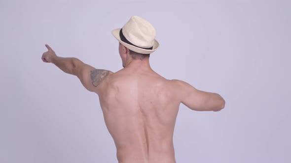 Rear View of Muscular Tourist Man Pointing Finger Shirtless