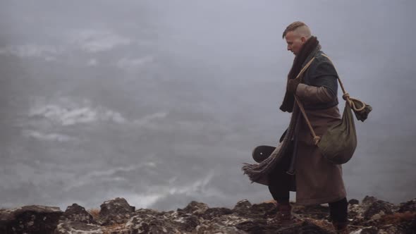 Man In Greatcoat Walking Through Misty And Rocky Landscape