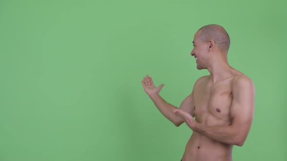Happy Bald Multi Ethnic Shirtless Man Showing To Back and Looking Surprised