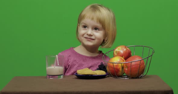 Girl Sitting at the Table and Eating Chocolate, Cookies and Drinks Cacao