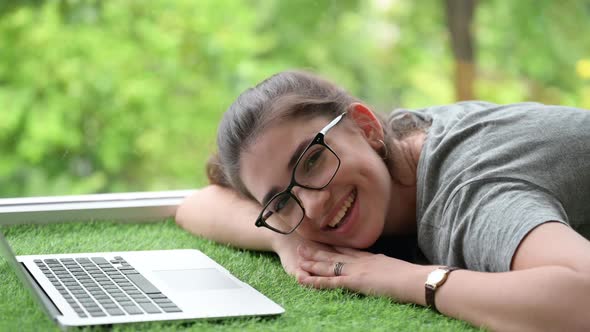 young woman working with a laptop at home. relaxing and happy lady looks at the camera.