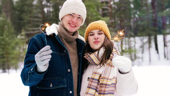 Happy Couple with Sparklers in Winter Forest