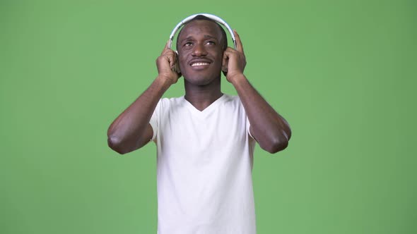 Young African Man Listening To Music Against Green Background