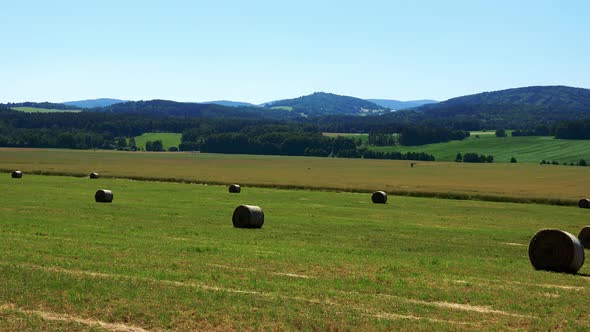 Field in Countryside with Haystack - Forests in Background - Sunny Day