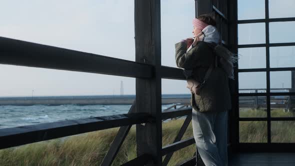 Woman in Warm Clothes Looks to the Cold Ocean