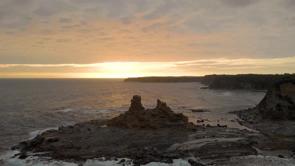 A high up forward moving aerial of eagles nest rock formation on bass coast Victoria with the sun se