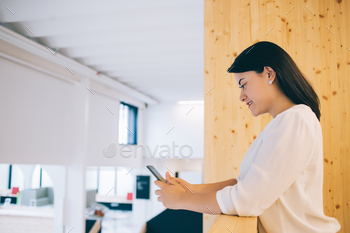 smiling millennial female manager downloading app on mobile phone for online communication