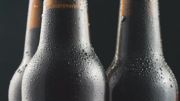 Three very cold beer bottles rotating on black background. Close up