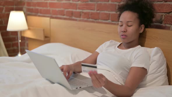 African Woman with Unsuccessful Online Payment on Laptop in Bed