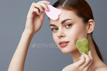 beautiful woman facial scraper skin care posing Gray background