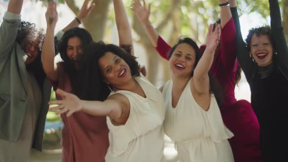 Happy Brides with Guests Lifting Arms and Looking at Camera