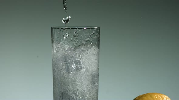 Carbonated liquid pouring into glass filled with ice 