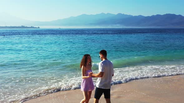 Couple dancing love song over sea waves splashing on white sand of exotic beach on a misty morning i