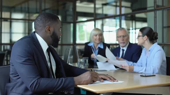 Male Company Employee Feeling Tired Listening to Shouting Colleagues in Office