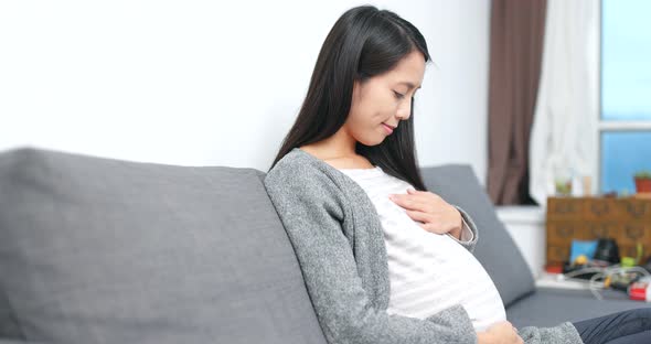 Young Pregnant woman looking of her tummy at home